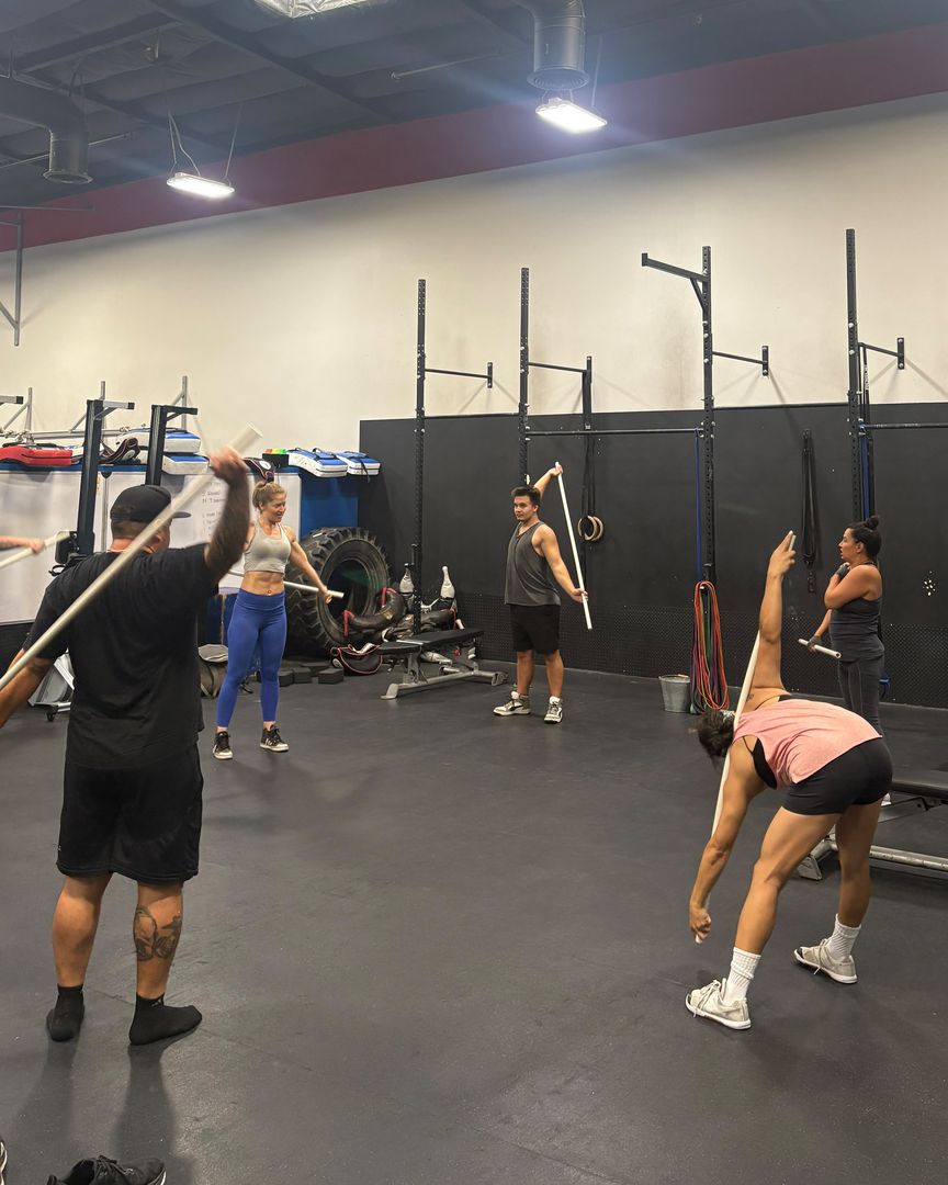 A coached group class warming up with mobility drills on the weight floor