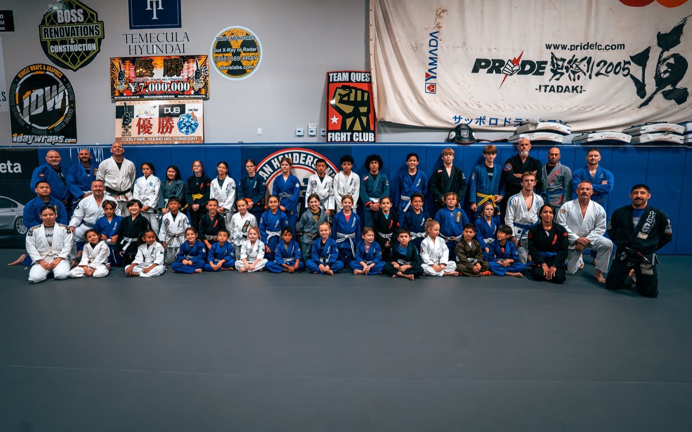 A large kids and adults jiu-jitsu class lined up on the mats